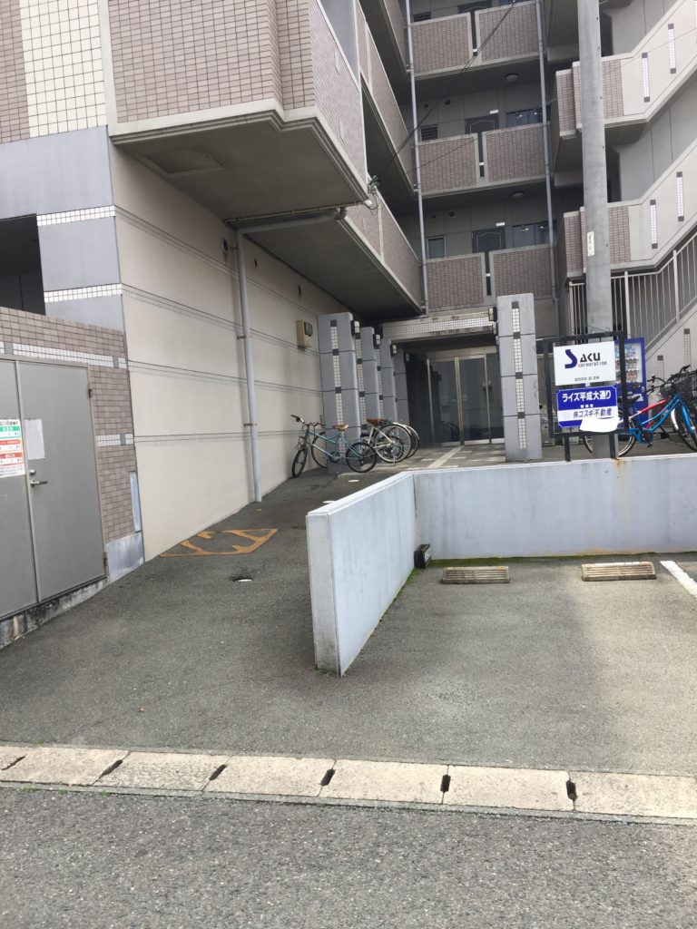 さらに100メートルほど曲がらずに直進します。 道が横切る左手前に建物があり、その手前に駐車場の入り口があります。No.21に駐車してください。
